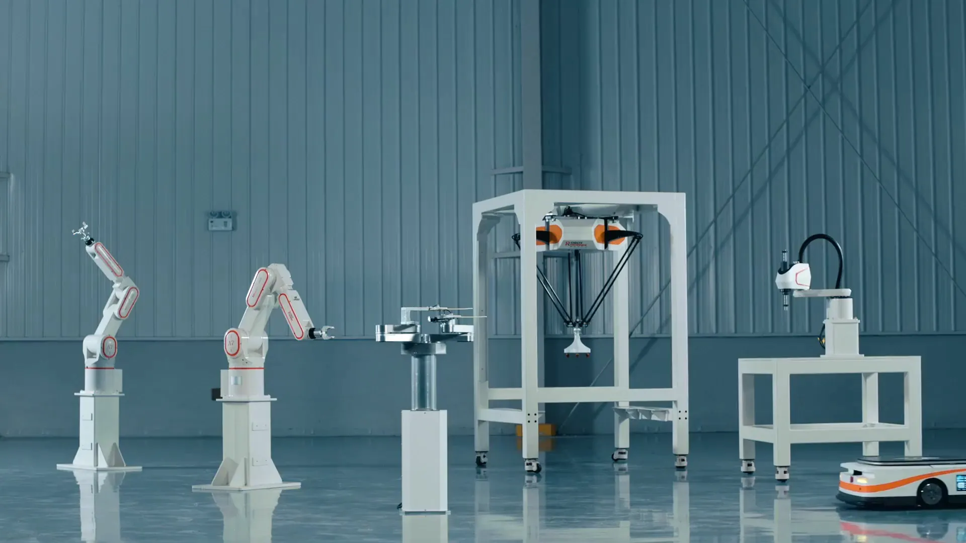 工場の床に、ロボットとAGVの製品群が一列に並んでいる様子